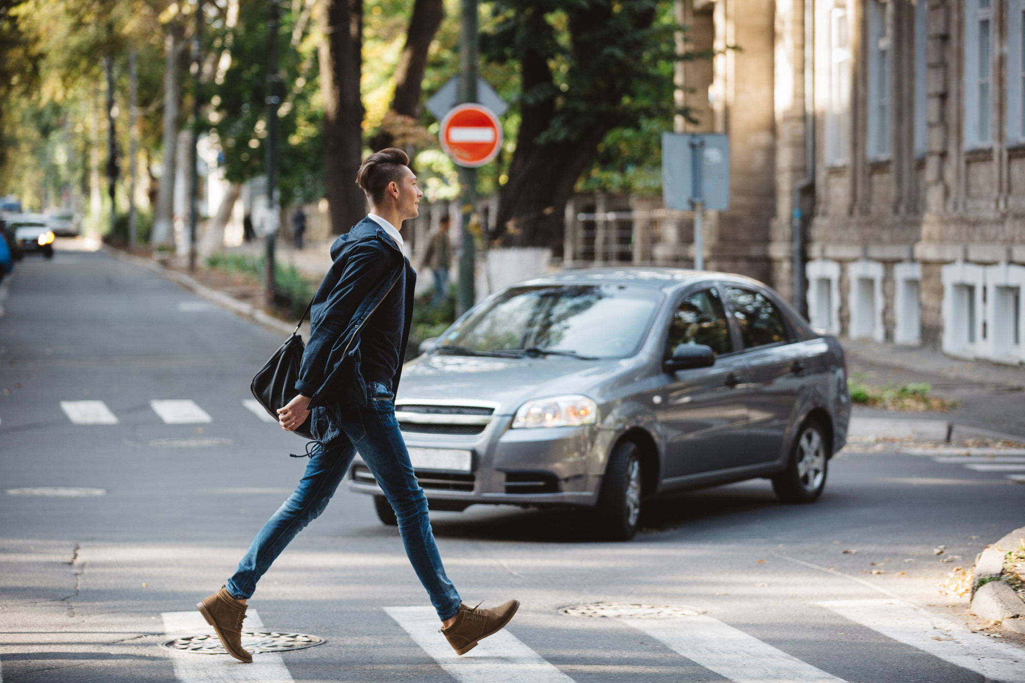 Person crossing the street with a car driving towards them