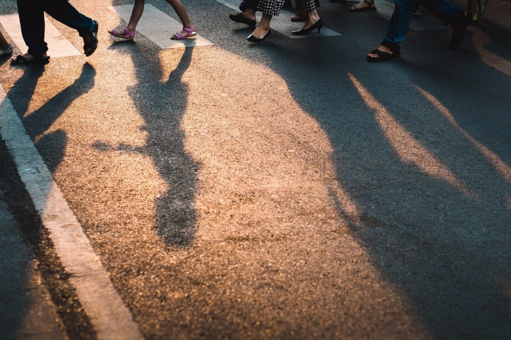 People navigating a pedestrian crosswalk at sunset in Rancho Cucamonga, illustrating the dangers of shadows and low light.