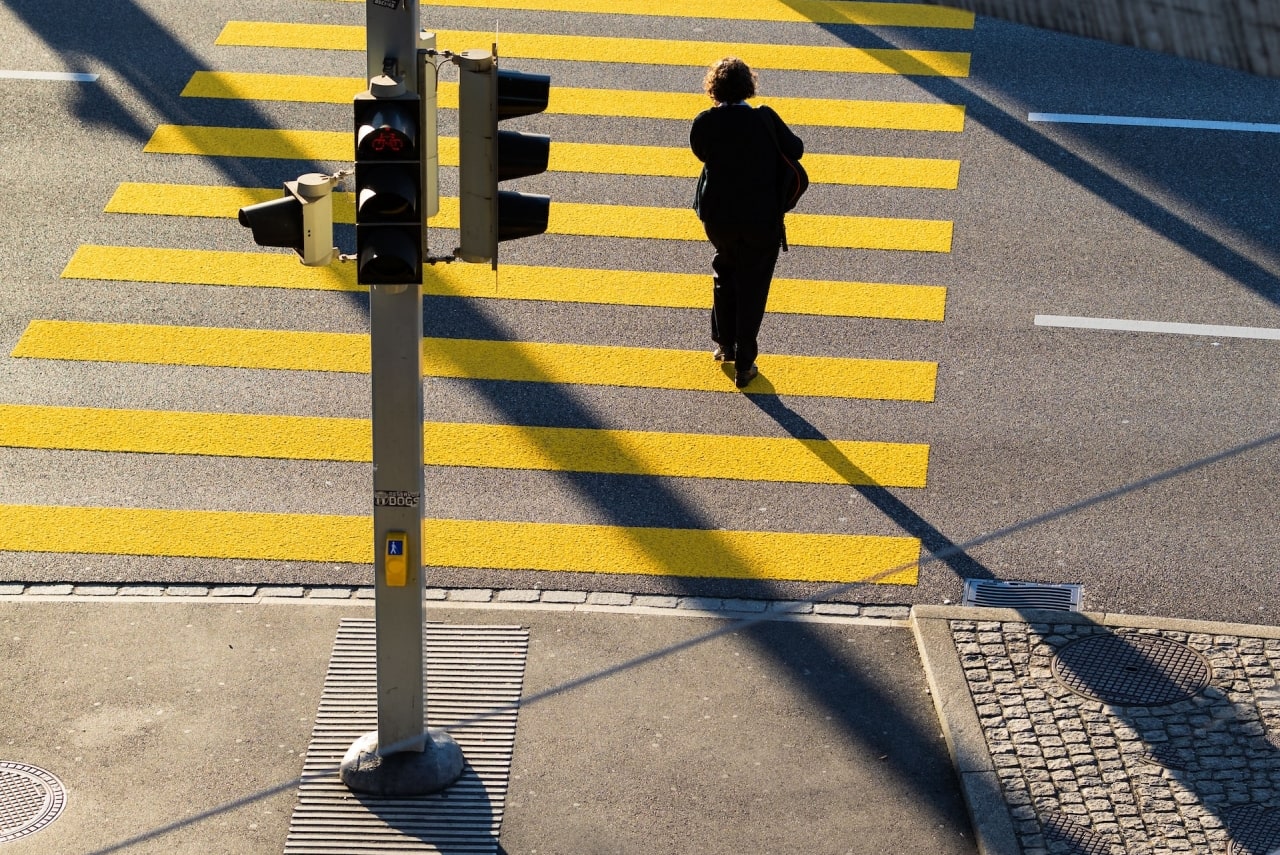 A woman in black clothing crosses a street at a marked crosswalk in Rancho Cucamonga, highlighting pedestrian safety concerns.
