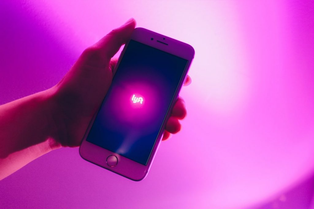 A person displays a phone illuminated by a purple light, symbolizing a Lyft accident settlement lawsuit.
