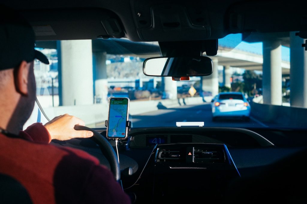 A driver using his phone while driving, emphasizing the need for caution and steps to take after an Uber accident.