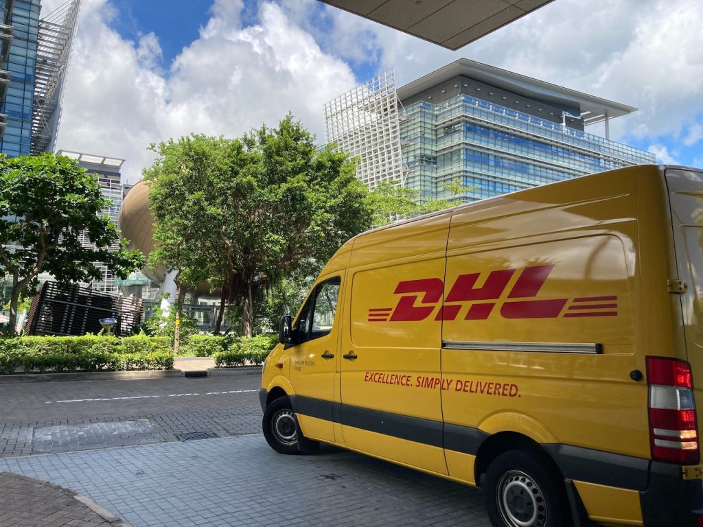 A DHL delivery van parked in front of a building, highlighting the importance of safe delivery practices to prevent accidents.