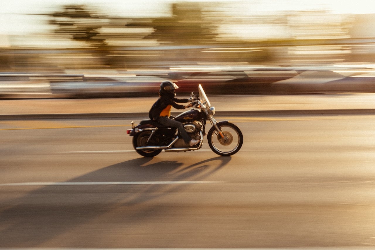 A motorcyclist navigates a busy city street, highlighting the risks of lane splitting in urban traffic.