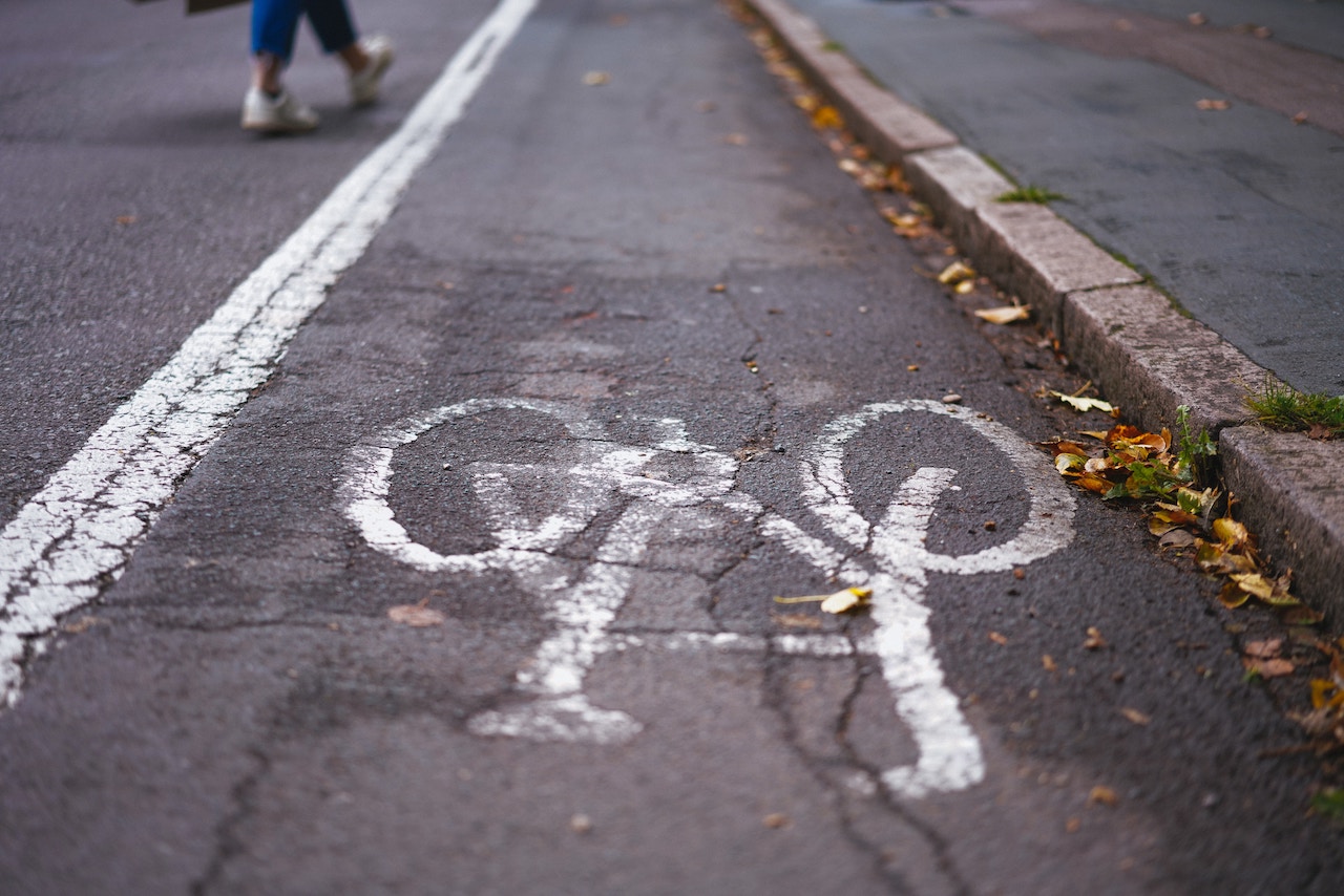 A pedestrian walks along a street featuring a bicycle painting, highlighting safety awareness for cyclists and walkers.