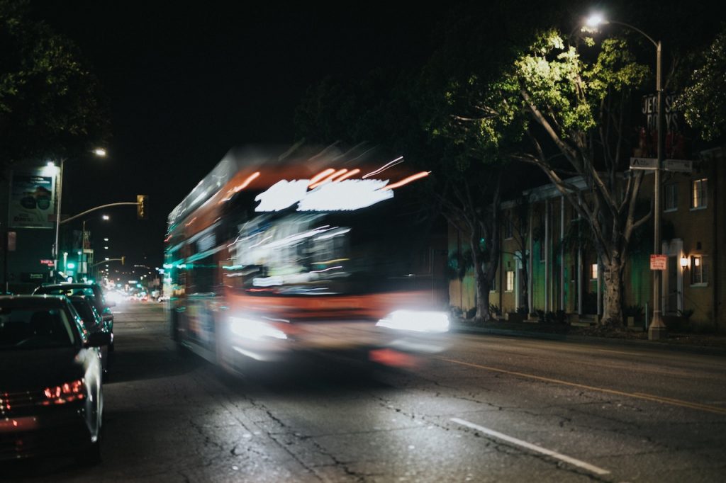 A bus moves along a dark street at night, emphasizing the safety concerns associated with bus travel in Rancho Cucamonga.