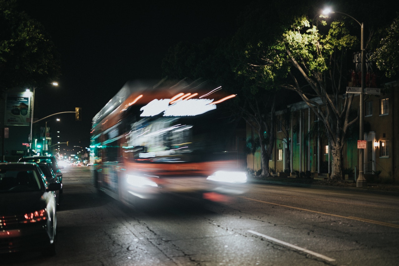 A bus moves along a dark street at night, emphasizing the safety concerns associated with bus travel in Rancho Cucamonga.