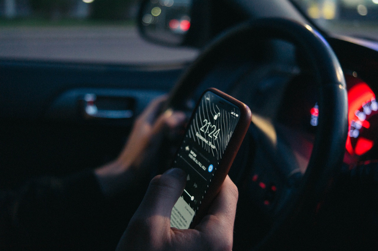 A driver holding a cell phone, highlighting the dangers of texting while driving in Rancho Cucamonga.